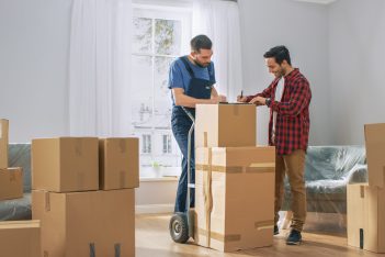 Happy,New,Homeowner,Welcomes,Professional,Mover,With,Hand,Truck,Full